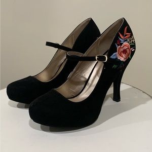 Black platform shoes with embellishments on heels.